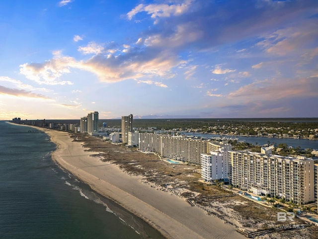 aerial view at dusk featuring a view of the beach and a water view