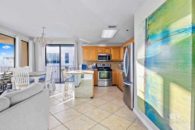 kitchen featuring backsplash, a notable chandelier, appliances with stainless steel finishes, a kitchen breakfast bar, and light tile patterned floors