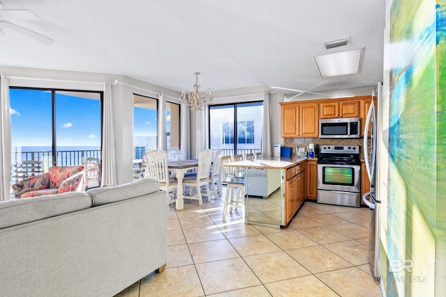 kitchen featuring light tile patterned floors, stainless steel appliances, tasteful backsplash, a textured ceiling, and pendant lighting