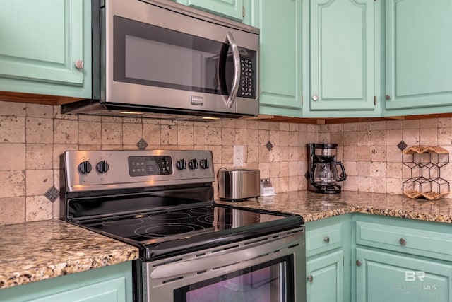 kitchen featuring green cabinets, decorative backsplash, and stainless steel appliances