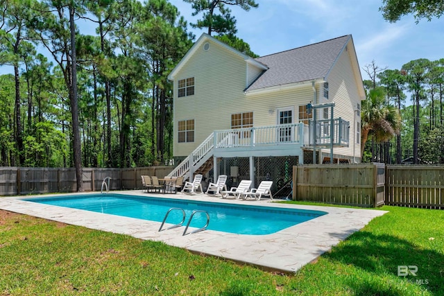 rear view of property featuring a pool side deck and a lawn