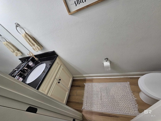 bathroom with baseboards, toilet, and wood finished floors