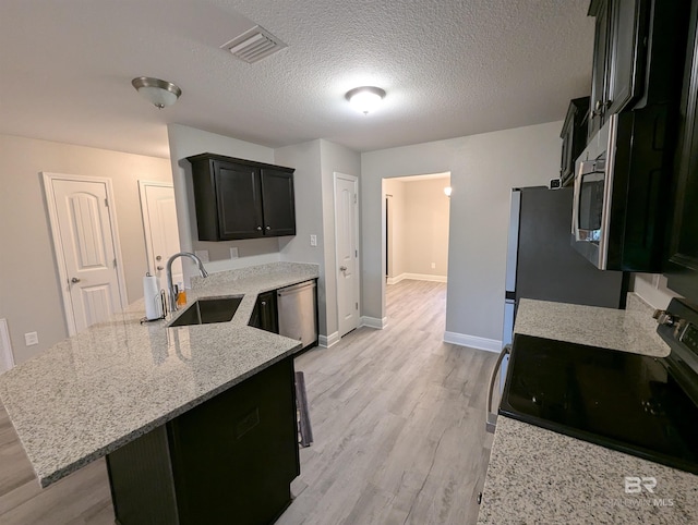 kitchen featuring visible vents, appliances with stainless steel finishes, light stone countertops, light wood-style floors, and a sink