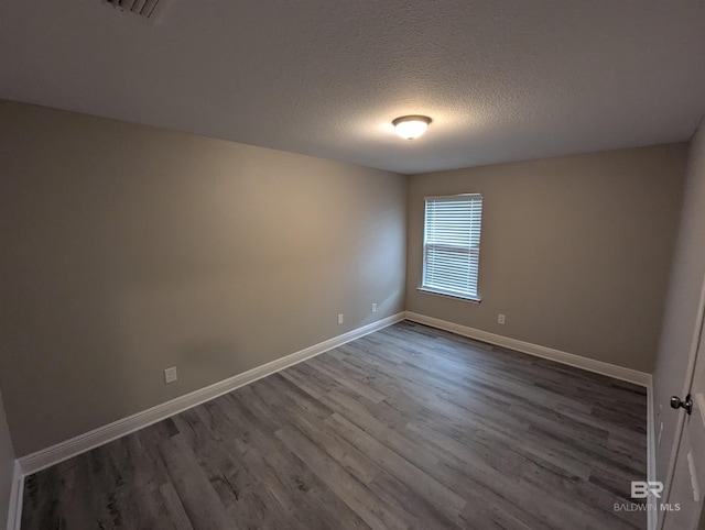 spare room featuring baseboards, dark wood finished floors, and a textured ceiling