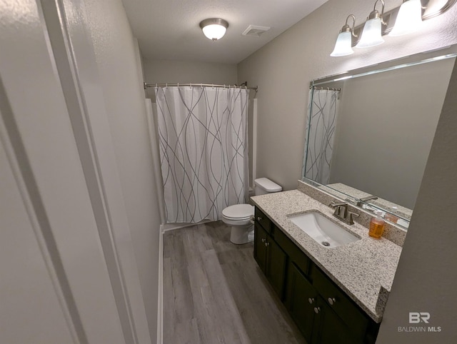 bathroom featuring visible vents, toilet, vanity, wood finished floors, and a shower with curtain