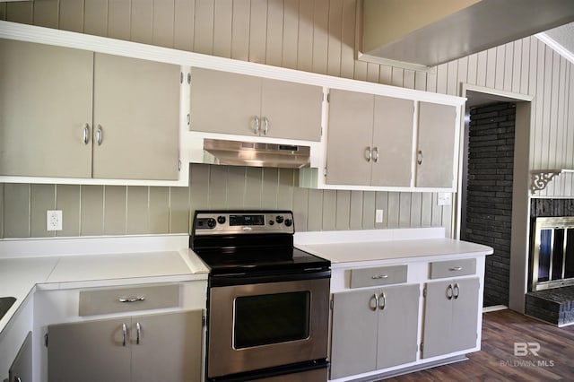 kitchen featuring stainless steel range with electric stovetop, a brick fireplace, dark hardwood / wood-style floors, and white cabinets