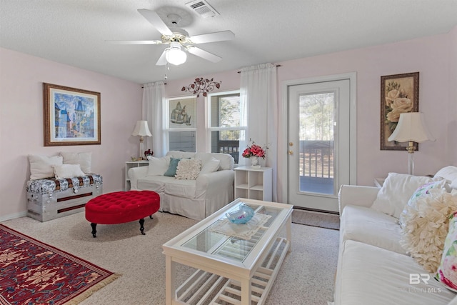 carpeted living room featuring ceiling fan and a textured ceiling