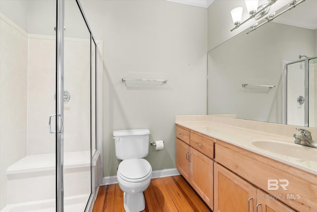 bathroom with crown molding, toilet, vanity, a shower with shower door, and hardwood / wood-style flooring