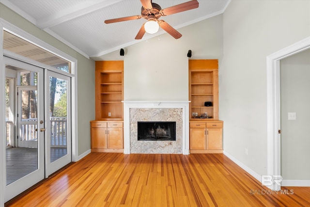 unfurnished living room with vaulted ceiling with beams, built in features, a fireplace, and french doors