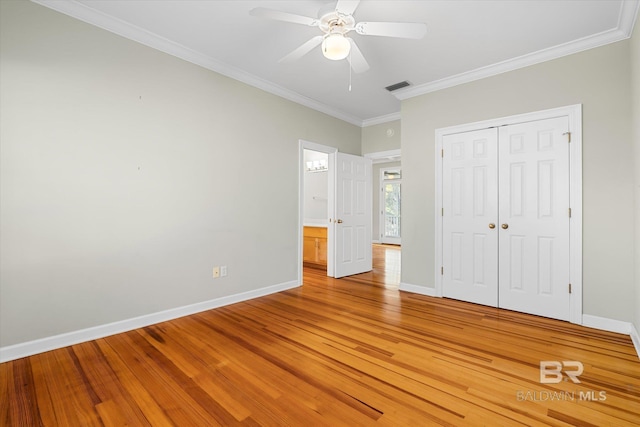 unfurnished bedroom featuring hardwood / wood-style flooring, ceiling fan, ornamental molding, and a closet