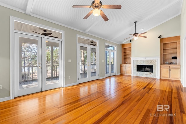 unfurnished living room with french doors, light wood-type flooring, built in features, and a premium fireplace