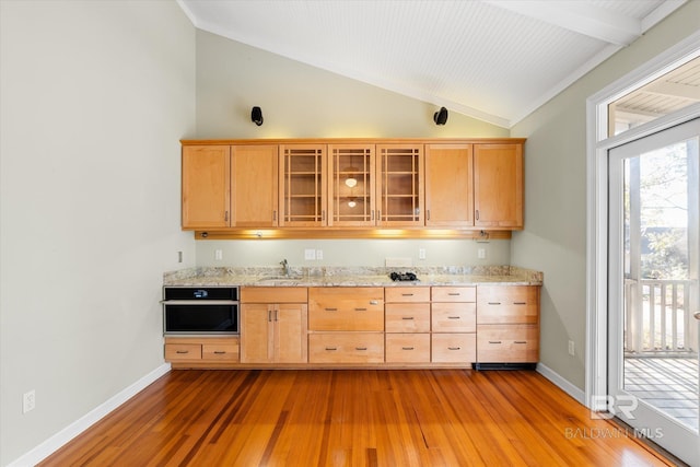 kitchen featuring light stone countertops, light hardwood / wood-style flooring, oven, and lofted ceiling