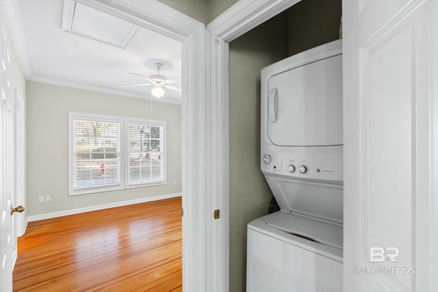 laundry room featuring hardwood / wood-style floors, ceiling fan, ornamental molding, and stacked washer and dryer