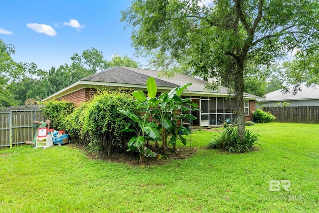 22091 Pecan Loop, Silverhill, AL 36576 - rear view of house featuring a fenced backyard, a shingled roof, a sunroom, and brick siding
