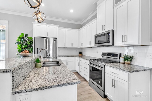 23901 Cypress Xing, Orange Beach, AL 36561 - kitchen featuring light wood-style flooring, ornamental molding, appliances with stainless steel finishes, a sink, and backsplash