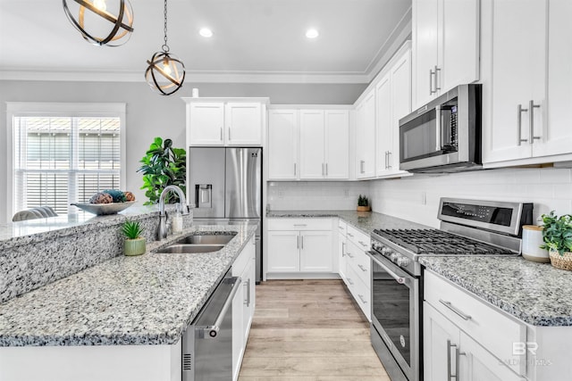23901 Cypress Xing, Orange Beach, AL 36561 - kitchen with white cabinets, ornamental molding, stainless steel appliances, a sink, and light wood-type flooring