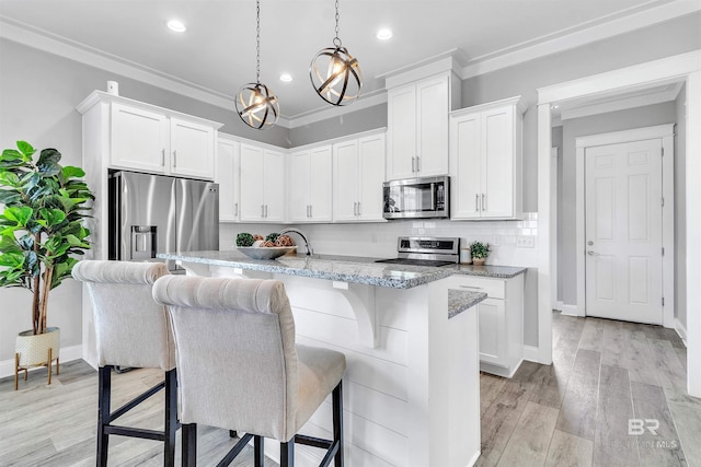 23901 Cypress Xing, Orange Beach, AL 36561 - kitchen featuring a kitchen bar, stainless steel appliances, backsplash, an island with sink, and light wood-style flooring