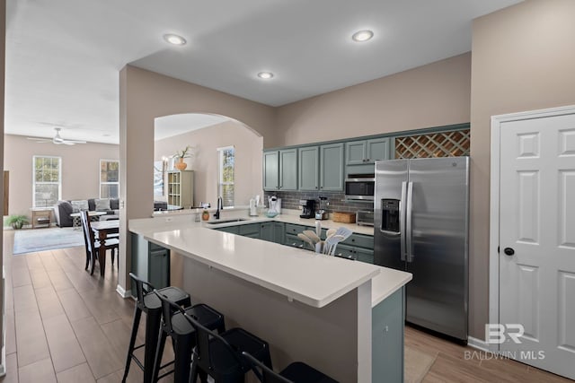 kitchen with ceiling fan, sink, kitchen peninsula, a breakfast bar area, and appliances with stainless steel finishes