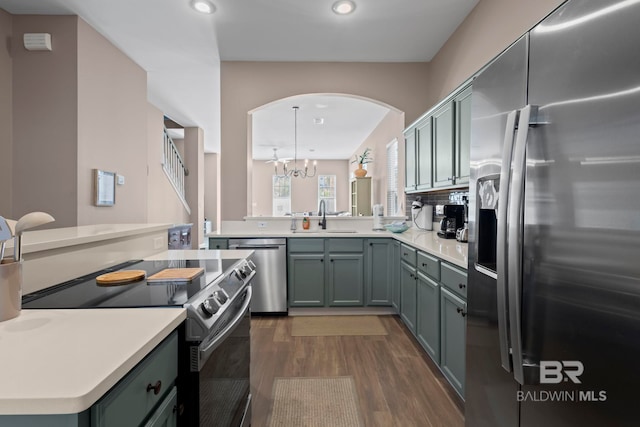 kitchen with appliances with stainless steel finishes, dark hardwood / wood-style flooring, sink, a chandelier, and hanging light fixtures