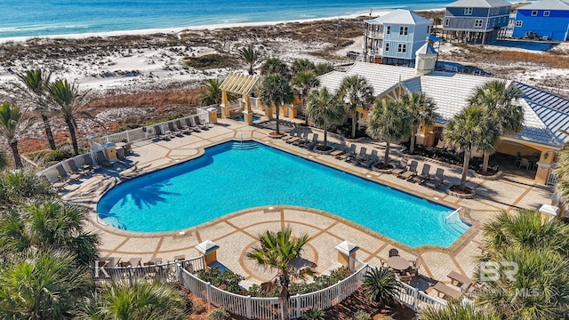 view of swimming pool with a beach view, a water view, and a patio area