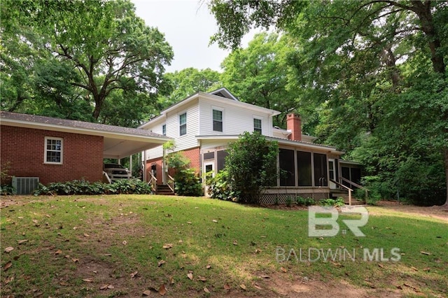 rear view of property with central AC unit, a yard, and a sunroom