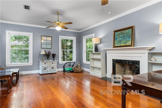 living room featuring hardwood / wood-style flooring, a high end fireplace, crown molding, and ceiling fan