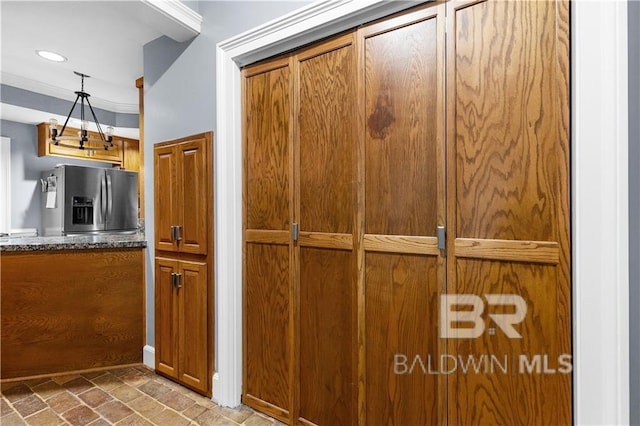 kitchen with stainless steel fridge with ice dispenser, hanging light fixtures, tile flooring, and dark stone countertops