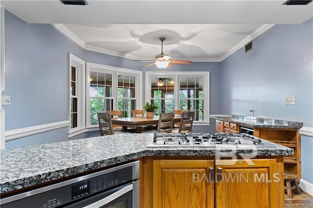 kitchen featuring appliances with stainless steel finishes, ceiling fan, dark stone counters, and ornamental molding