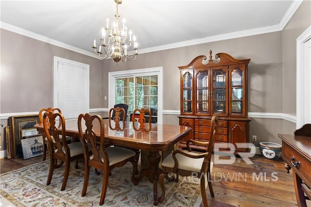 dining space with hardwood / wood-style floors, an inviting chandelier, and ornamental molding