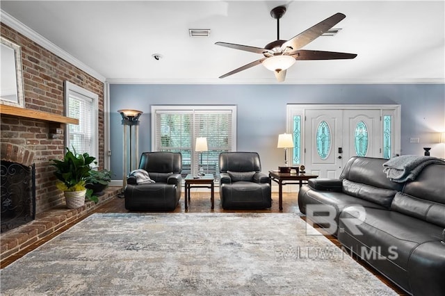 living room with brick wall, ceiling fan, a brick fireplace, and crown molding