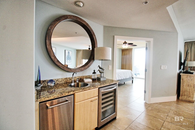 interior space featuring sink, wine cooler, stainless steel dishwasher, dark stone countertops, and light brown cabinetry