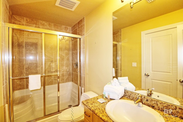 bathroom with vanity, a shower with shower door, and toilet