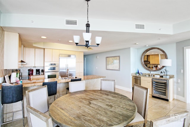 dining area with wine cooler, a notable chandelier, and sink