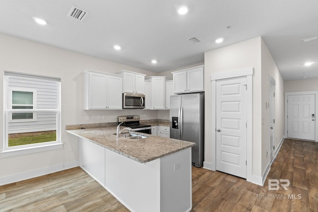 kitchen with white cabinetry, wood-type flooring, stainless steel appliances, and kitchen peninsula