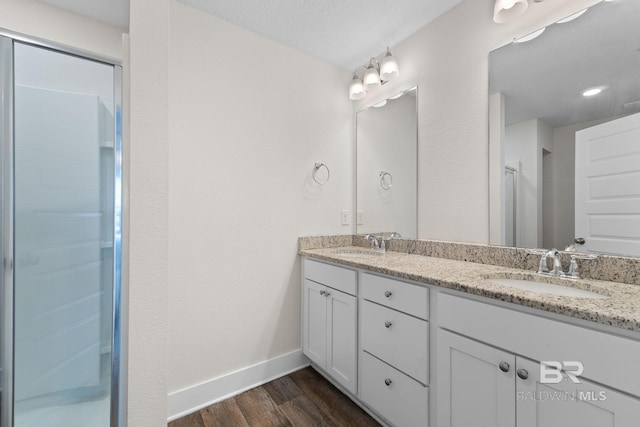 bathroom with vanity, hardwood / wood-style floors, a textured ceiling, and a shower