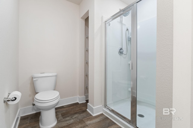 bathroom featuring hardwood / wood-style flooring, an enclosed shower, and toilet