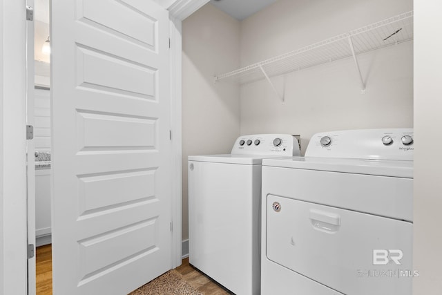 washroom with washing machine and clothes dryer and light hardwood / wood-style flooring