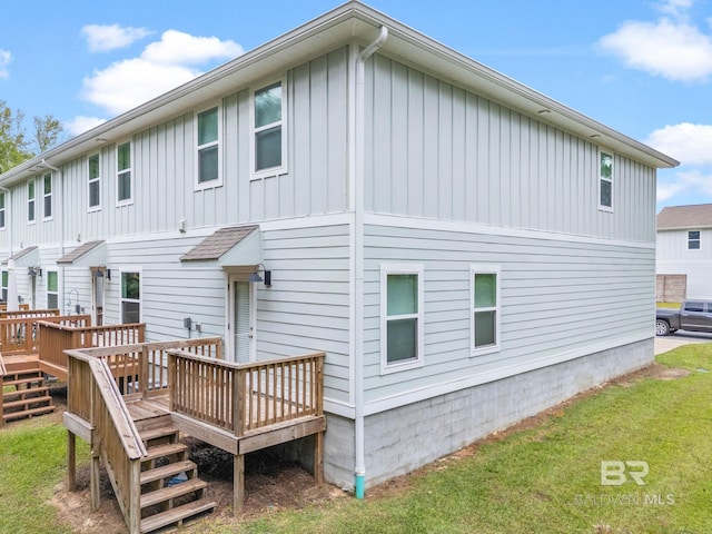 back of property featuring a wooden deck and a lawn