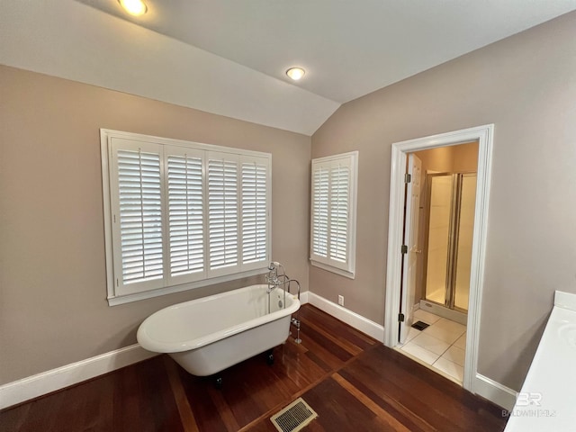 151 Mockingbird Ln, Atmore, AL 36502 - bathroom with wood finished floors, a soaking tub, a stall shower, baseboards, and lofted ceiling