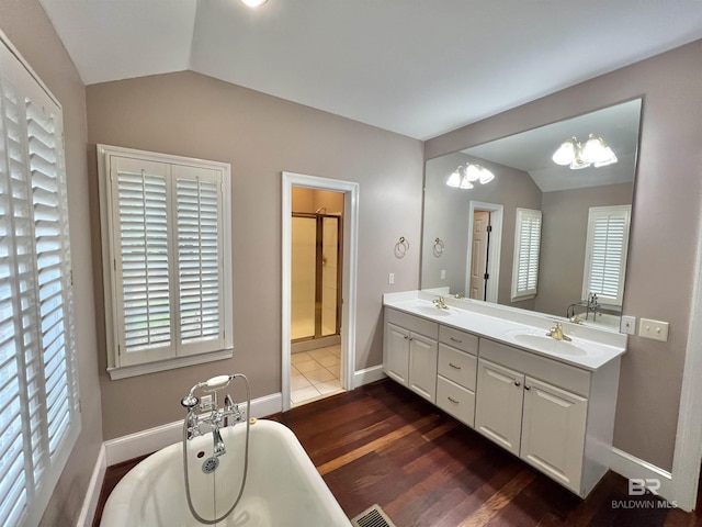 151 Mockingbird Ln, Atmore, AL 36502 - bathroom featuring vaulted ceiling, a freestanding tub, double vanity, wood finished floors, and a shower stall