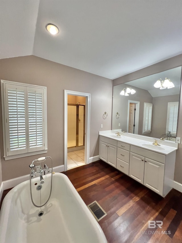 151 Mockingbird Ln, Atmore, AL 36502 - full bathroom with lofted ceiling, a soaking tub, double vanity, wood finished floors, and a chandelier