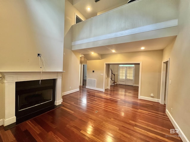 151 Mockingbird Ln, Atmore, AL 36502 - unfurnished living room with a towering ceiling, wood finished floors, a fireplace, baseboards, and stairway