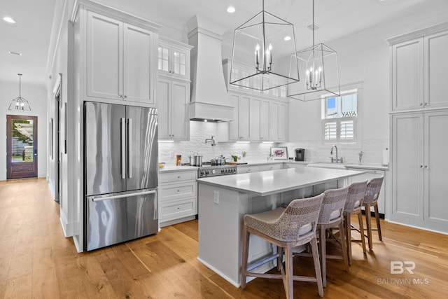 kitchen featuring decorative backsplash, custom exhaust hood, light hardwood / wood-style floors, a center island, and high end refrigerator