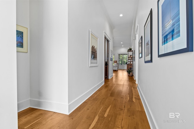 corridor with hardwood / wood-style floors and crown molding