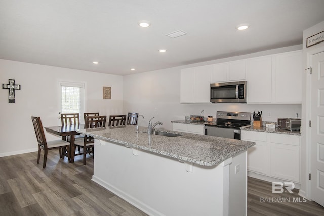 10909 Blacktail Loop, Pensacola, FL 32526 - kitchen with appliances with stainless steel finishes, dark wood finished floors, white cabinets, a kitchen breakfast bar, and recessed lighting