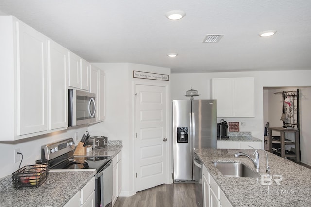 10909 Blacktail Loop, Pensacola, FL 32526 - kitchen with stainless steel appliances, wood finished floors, white cabinets, light stone countertops, and recessed lighting