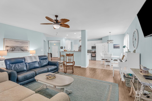living room featuring light wood finished floors, a ceiling fan, and recessed lighting