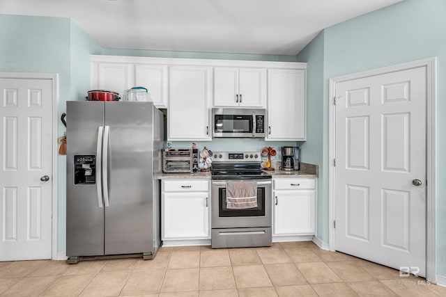 kitchen with light stone countertops, a toaster, light tile patterned flooring, white cabinets, and appliances with stainless steel finishes