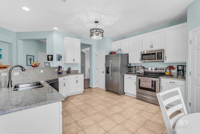 kitchen with a peninsula, a sink, white cabinetry, appliances with stainless steel finishes, and light stone counters