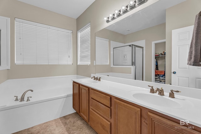 bathroom with a walk in closet, a bath, a stall shower, and a sink